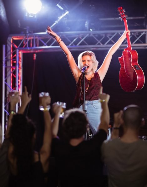 Female performer with arms raised singing during music event